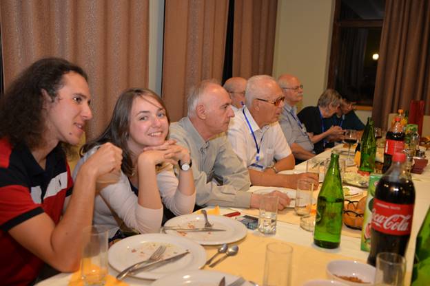 A group of people sitting at a table eating food

Description generated with very high confidence