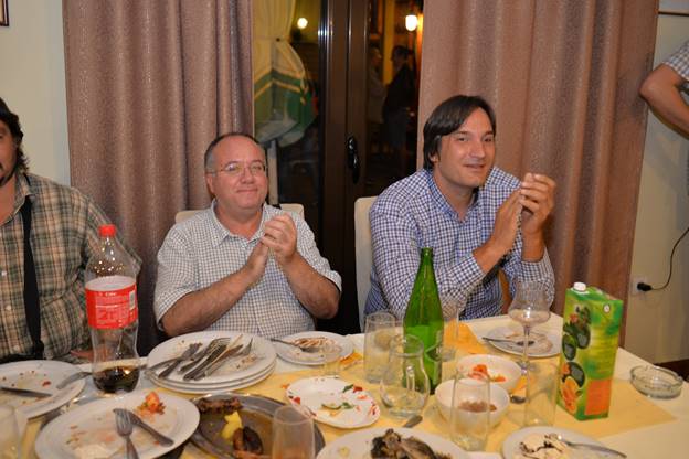 A group of people sitting at a table eating food

Description generated with very high confidence